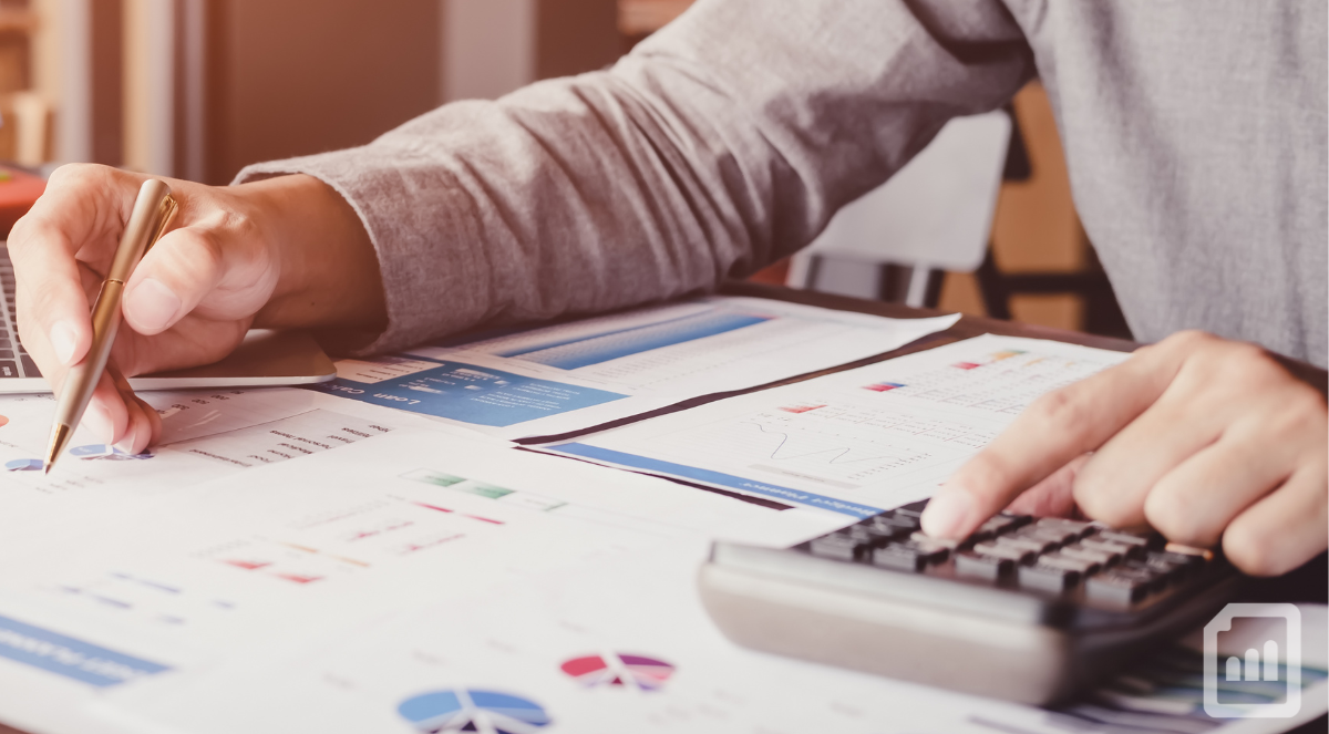 a close-up of financial charts and a man's hands using a pen and calculator