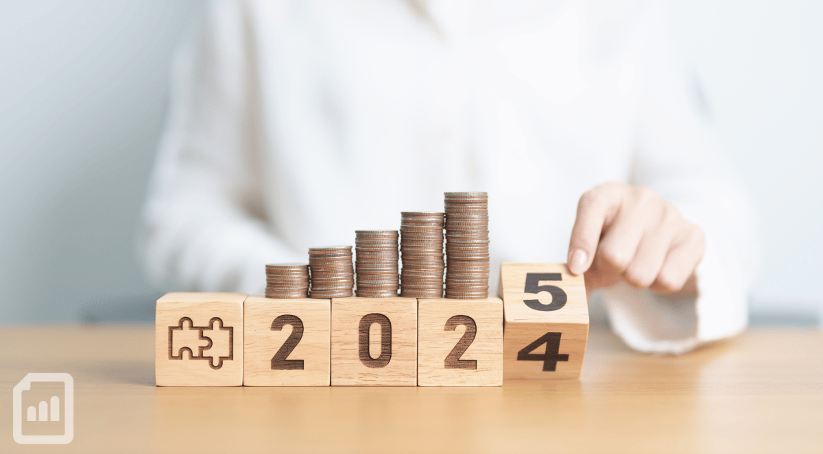 a close-up of coins and wooden blocks showing 2024 and a hand flipping the 4 to 5