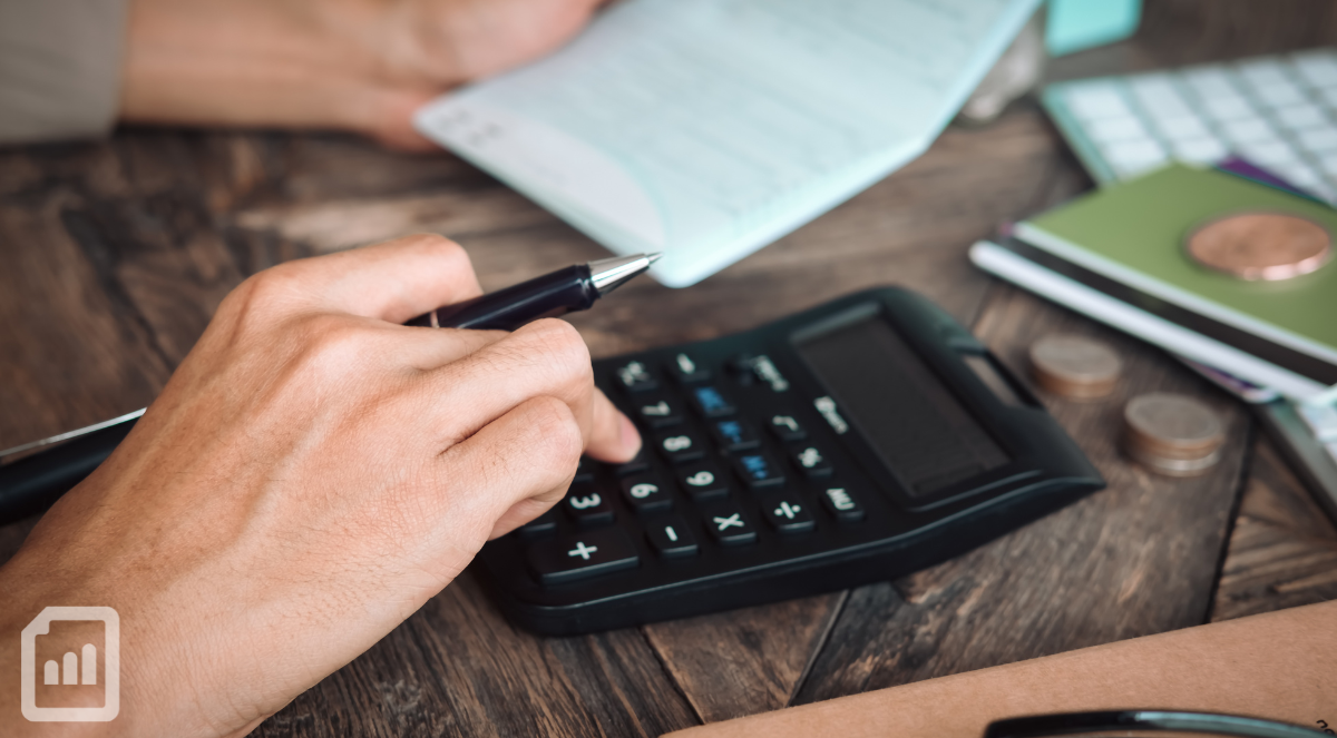 close-up of someone's hand using a calculator and holding a pen